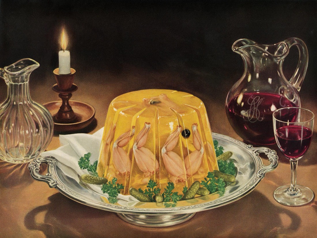 A sliced mustard-yellow terrine with frog legs suspended inside, on a silver platter.